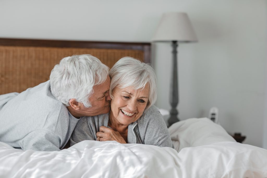 A older couple enjoying time together in the bedroom.