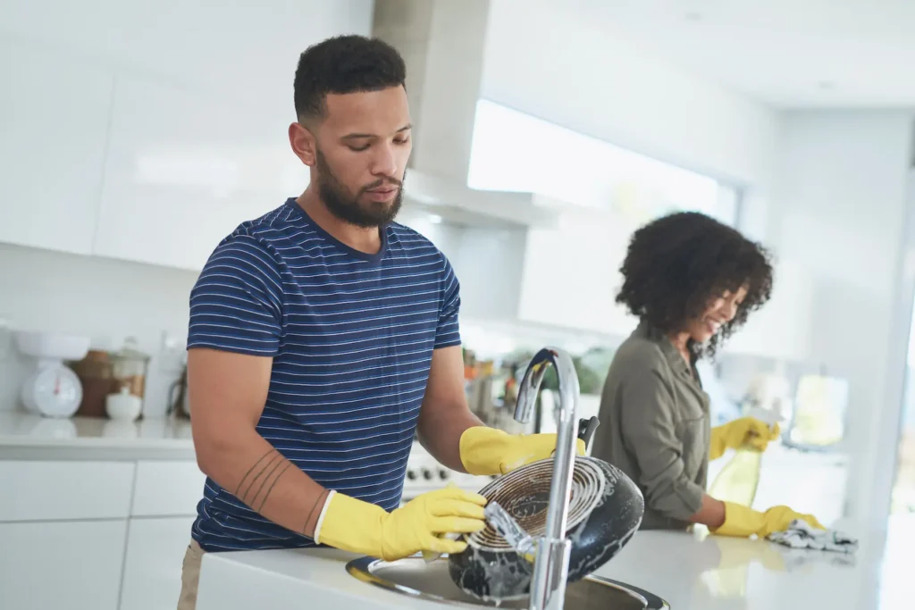 A young couple caught up in roommate syndrome working together in the kitchen.
