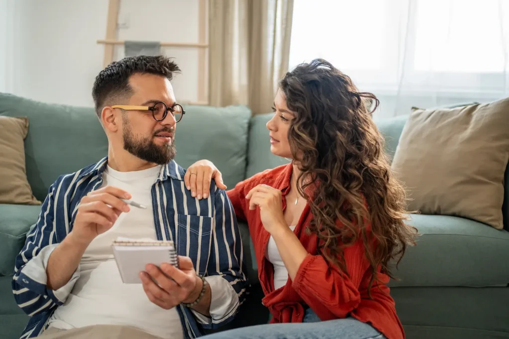 A couple having a relationship check-in. One partner is listening to the other and taking notes.