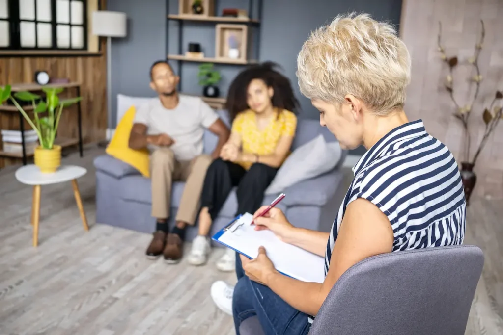 A couples therapist trying to do notes while meeting a couple in session.