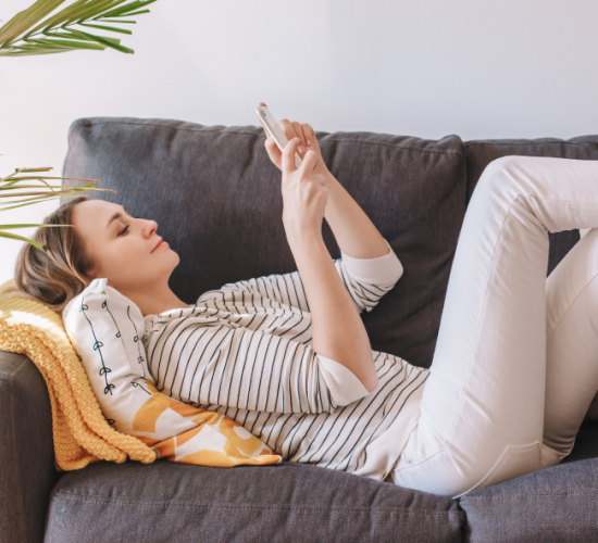 Image of woman lying on couch looking aty her phone